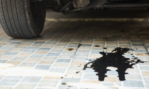 Oil leak from the car's engine on the parking lot. Car inspection and maintenance service