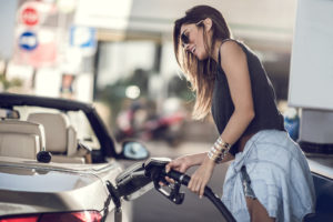 Woman refueling the gas tank at fuel pump.